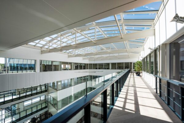 Lichte en moderne binnenruimte van een kantoorgebouw aan de Thomas R. Malthusstraat met glazen dak en loopbrug.